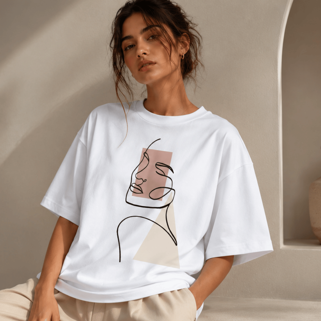 Women's oversized white abstract line art t-shirt with blush pink geometric print — seated front pose